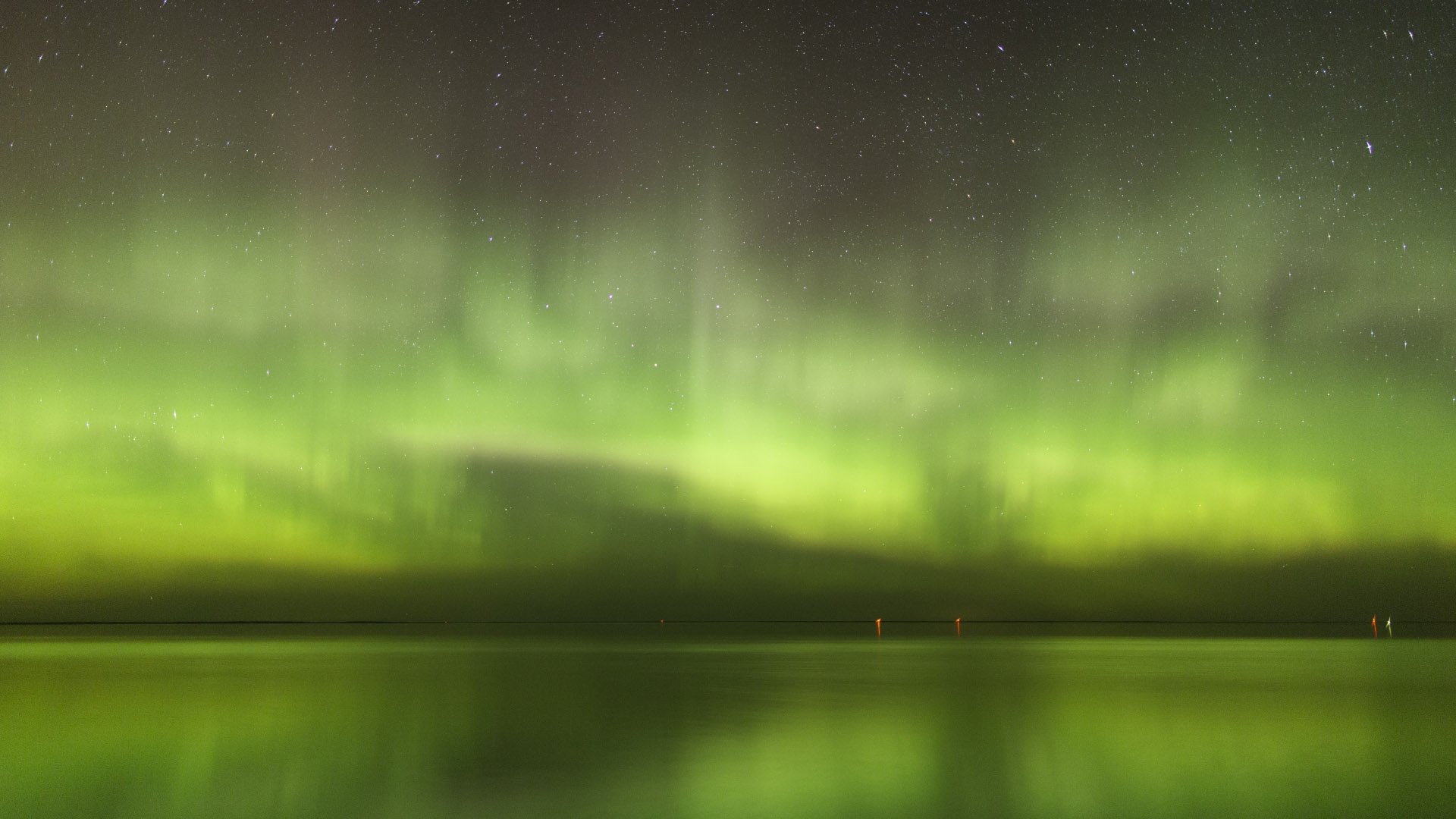 Vivid green aurora borealis over a northern Minnesota lake, photographed by Bob Conzemius